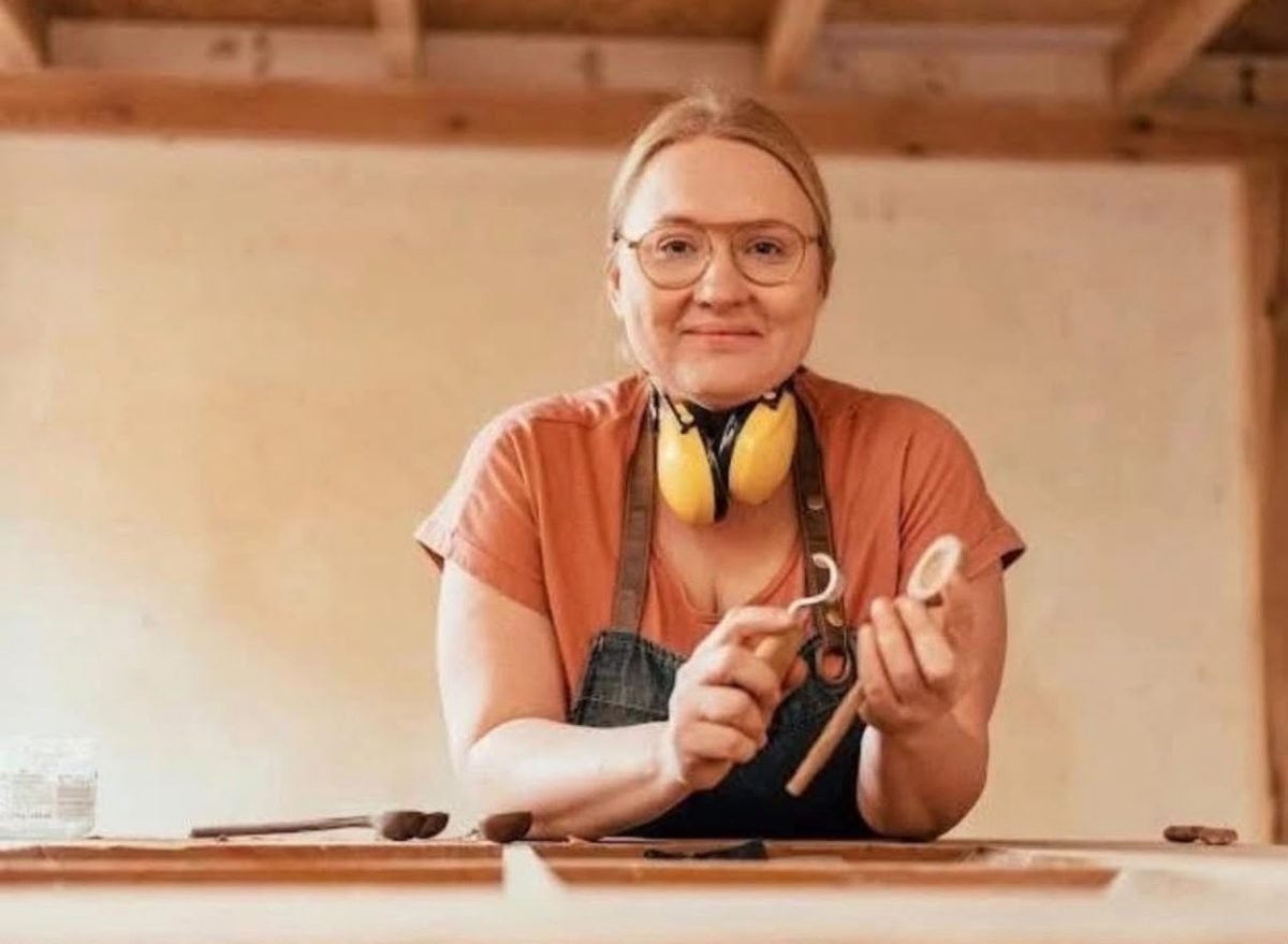 Die Gründerin von Berlin Wood Sisters lächelnd in der Werkstatt, mit einem handgeschnitzten Löffel